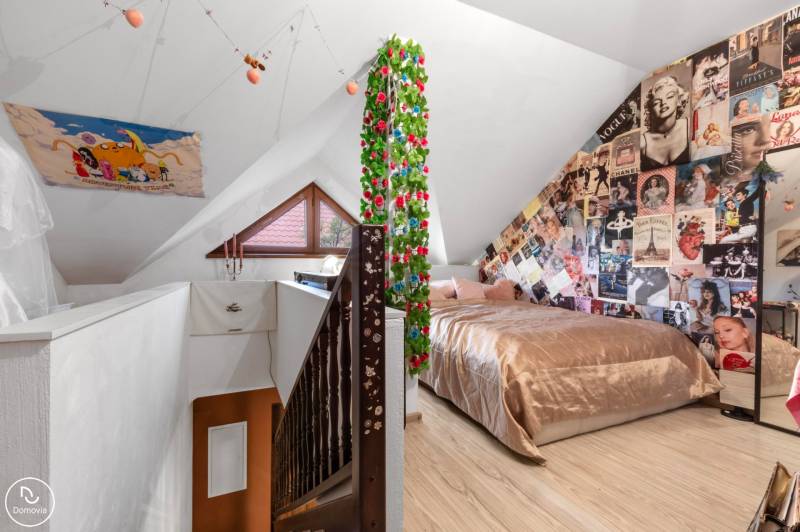 Attic room in a family house with posters, a bed, and a wooden decor floor.