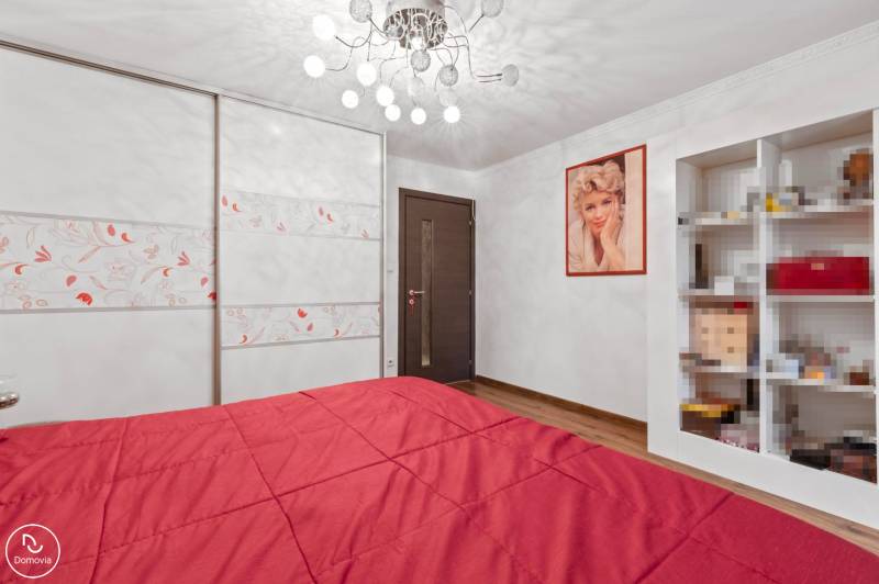 A bedroom in a family house with a red bed, a wooden decor floor, and a wardrobe.
