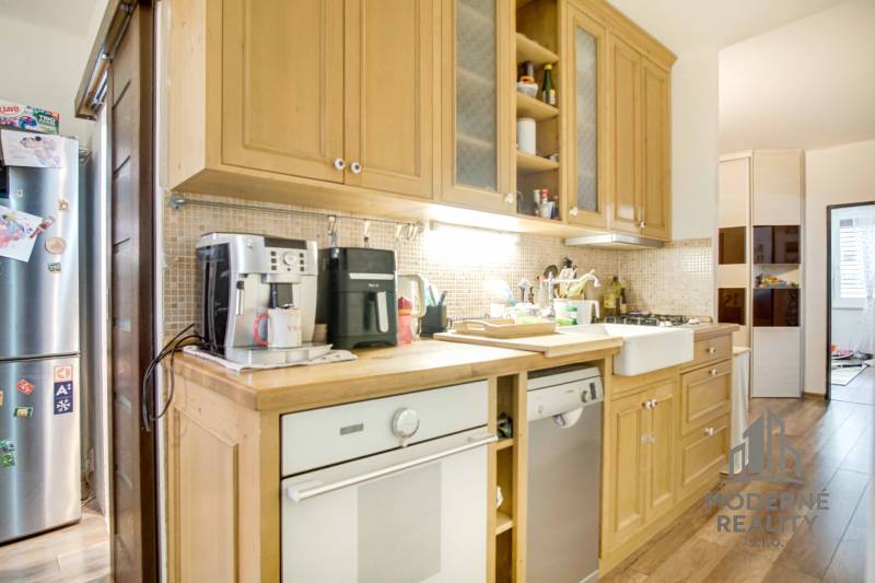 A kitchen with wooden cabinets and appliances in a 3-room apartment.