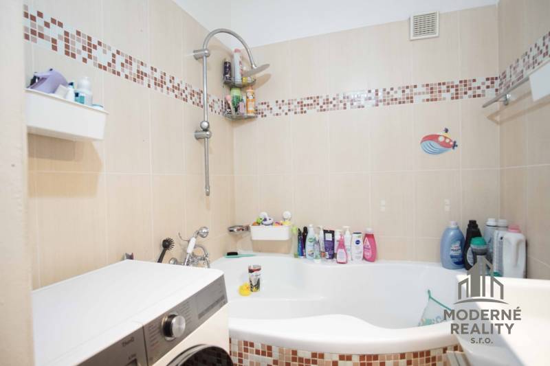 A bathroom in a 3-room apartment with a bathtub, tiles, and a washing machine.