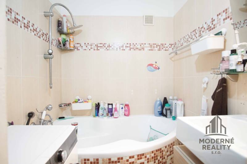 Bathroom with a bathtub in a 3-room apartment, tiles with a mosaic pattern, shower faucet.