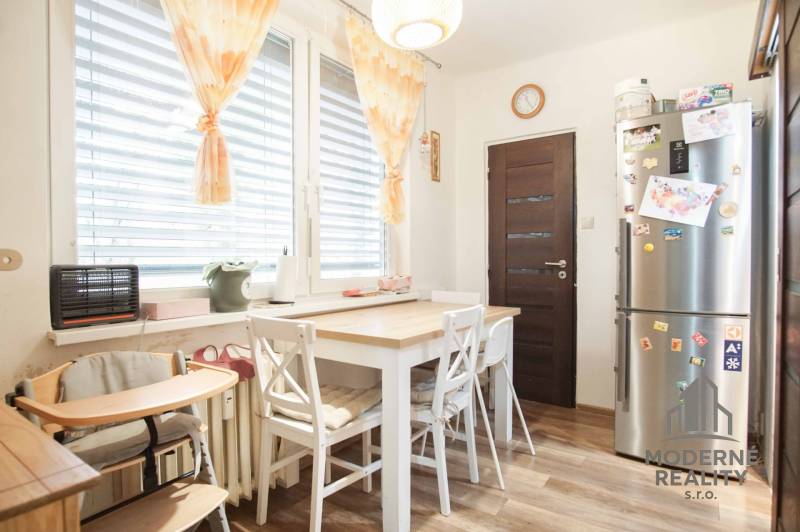 Dining room with a kitchen table, chairs, and a floor with a wooden decor, 3-room apartment.