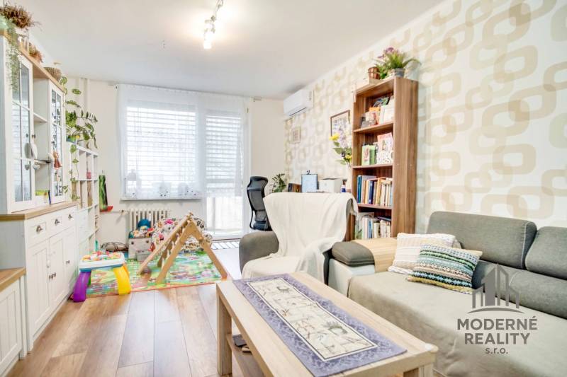 Living room in a 3-room apartment with a wooden decor floor and a play area for children.