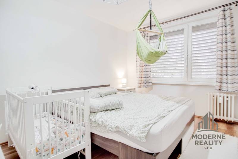 Bedroom in a 3-room apartment with a bed, a crib, and a swing, floor with wooden decor.
