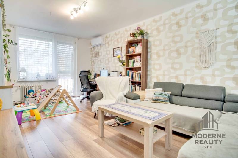 Living room in a three-room apartment with a wooden decor floor and a work corner.