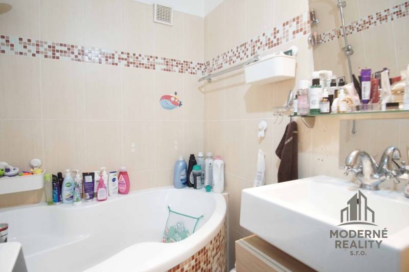 Bathroom in a 3-room apartment with a bathtub, sink, and shelves with cosmetics.