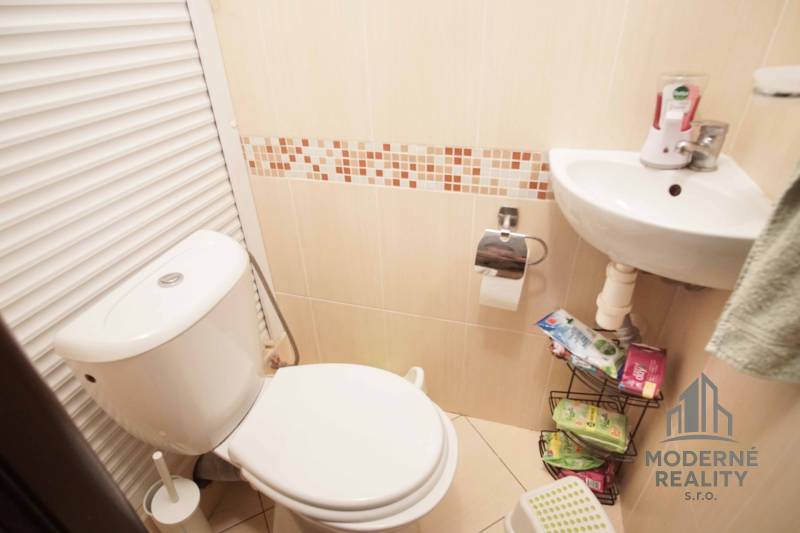 Bathroom with toilet and sink in a 3-room apartment, beige tiles.