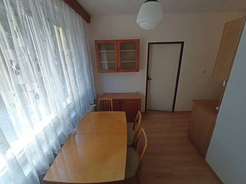 Dining area in a 2-room apartment with wooden floor decor and curtains.