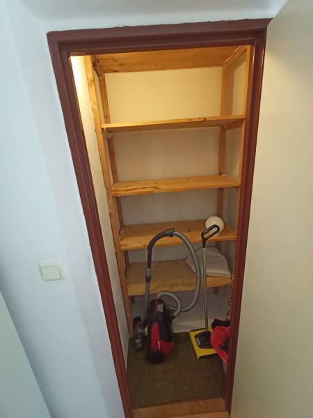Storage space with shelves and a vacuum cleaner in a 2-room apartment.