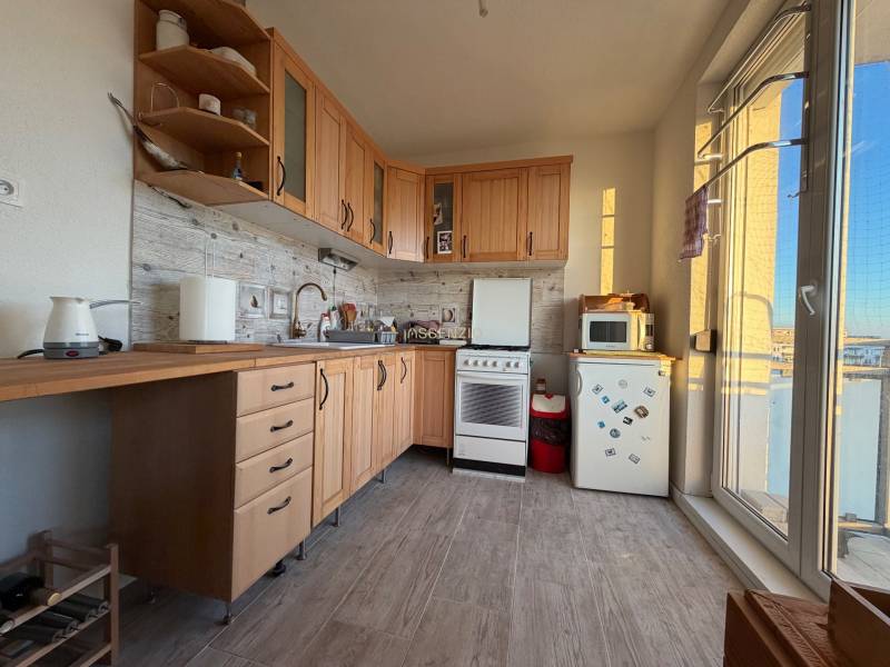 A kitchen in a 2-room apartment with wooden decor and appliances, including a small stove.