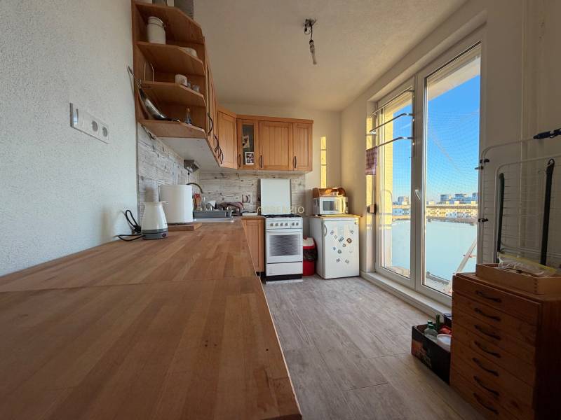 A kitchen in a 2-room apartment with wooden decor and appliances, view from the balcony.