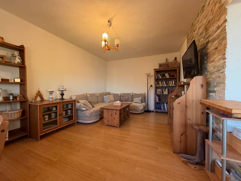 Living room with a sofa, wood-decor floor, bookshelf, and a TV on the wall.