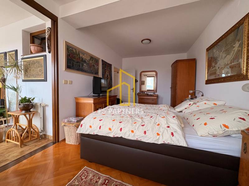 A room in a 5 or more bedroom apartment with a bed, art on the walls, and a floor with a wood decor.