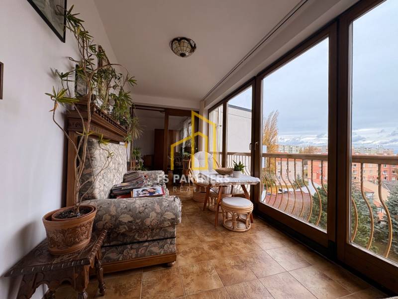 A spacious balcony in a 5 or more room apartment with large windows and cozy seating.