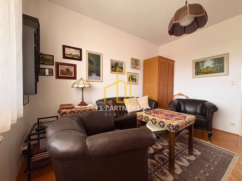 A room of a five or more-bedroom apartment with leather furniture and a floor with a wooden decor.
