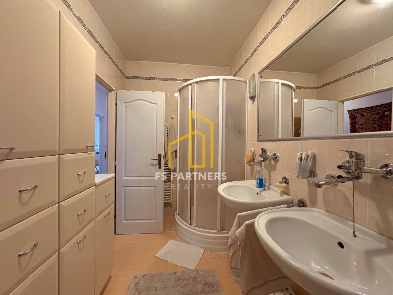 A bathroom with a double sink, shower, and storage space in a 5-room apartment.