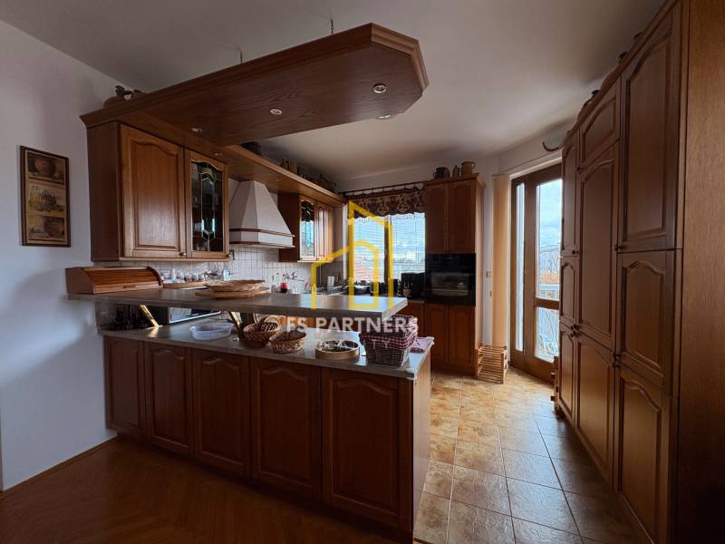 A kitchen in a 5 or more room apartment with built-in wooden cabinets and a floor with a wood decor.