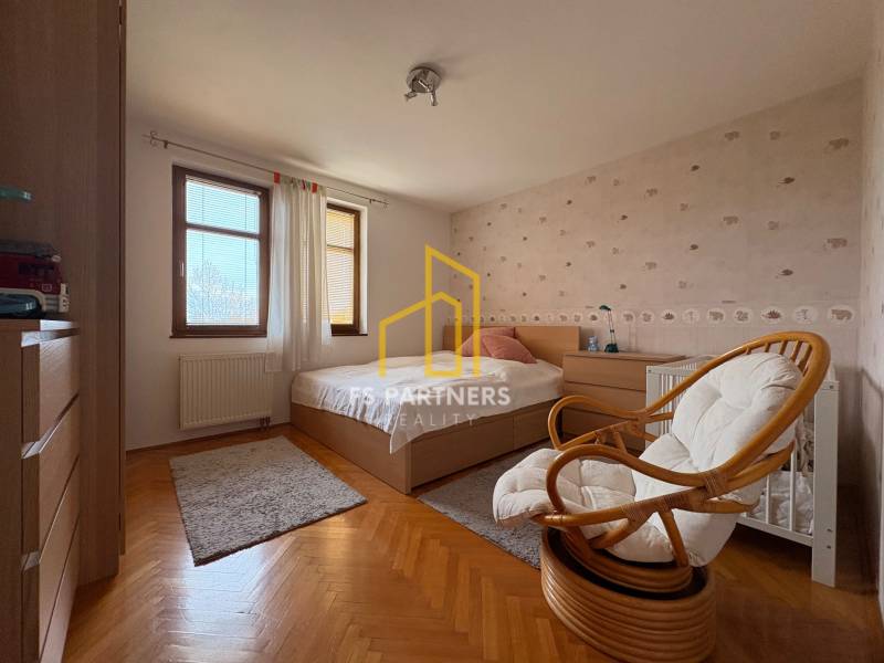 A room with a bed and a chair in a 5 or more room apartment. Floor with wood decor.