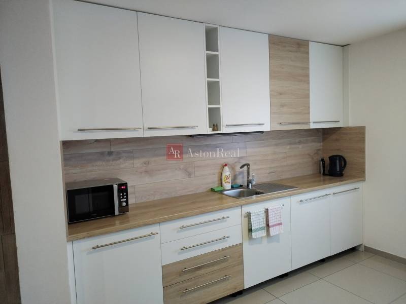 A kitchen in a cottage with white cabinets and a wood-patterned floor.