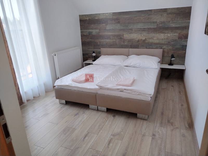 A bedroom in a cabin with a double bed, wooden wall decor, and light flooring.