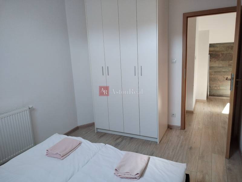 A bedroom in a cottage with a white wardrobe and a wooden decor floor.