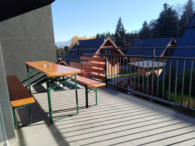 The balcony of the cottage in Stráne in Martin with a wooden bench and table, surrounded by nature.