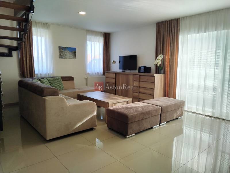Living room in a cottage with a sofa, television, and wooden decor flooring.
