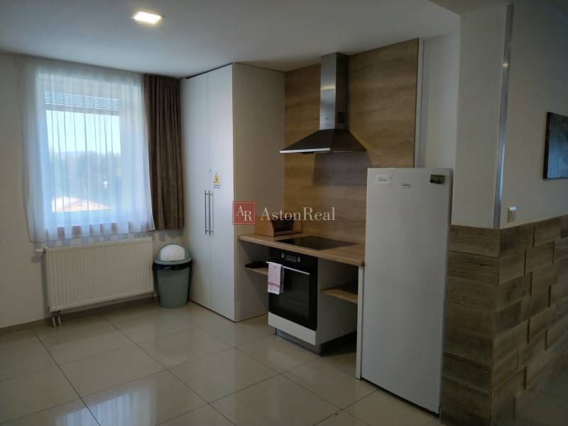 Interior of a cottage with a kitchenette and white appliances, tiled floor.
