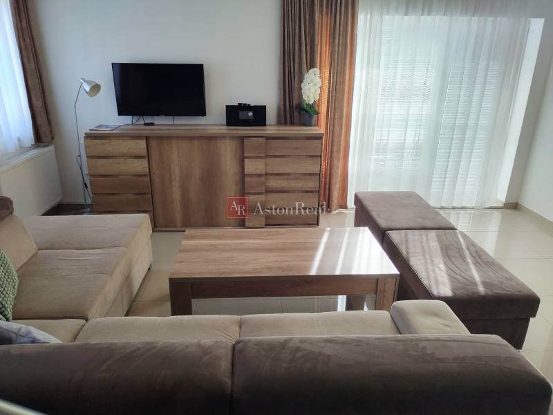 Living room of the cottage with a sofa, TV on a dresser, and a floor with a wooden decor.