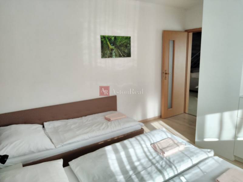 Two beds in a room with a painting on the wall and a door in a cabin.