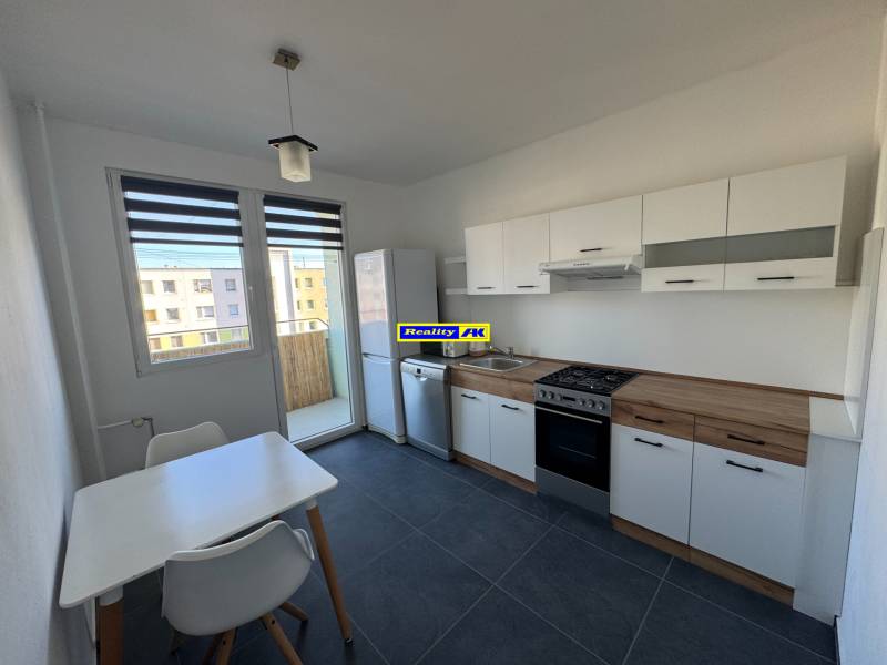 A kitchen in a 3-room apartment with white furniture and a dining table.