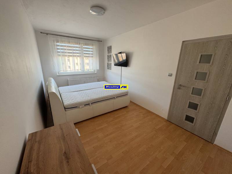 A bedroom with a double bed, wooden decor flooring, and furniture in a 3-room apartment.