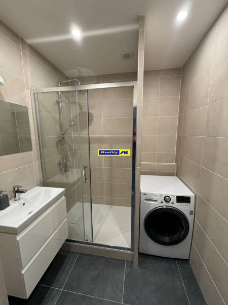 A bathroom in a 3-room apartment with a shower and a washing machine, tiled floor.