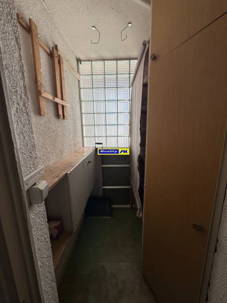 Storage space in a 3-room apartment with shelves and a glass wall.