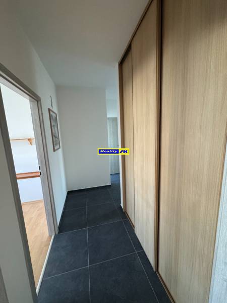 A hallway in a 3-room apartment with dark tiles and a built-in wardrobe.