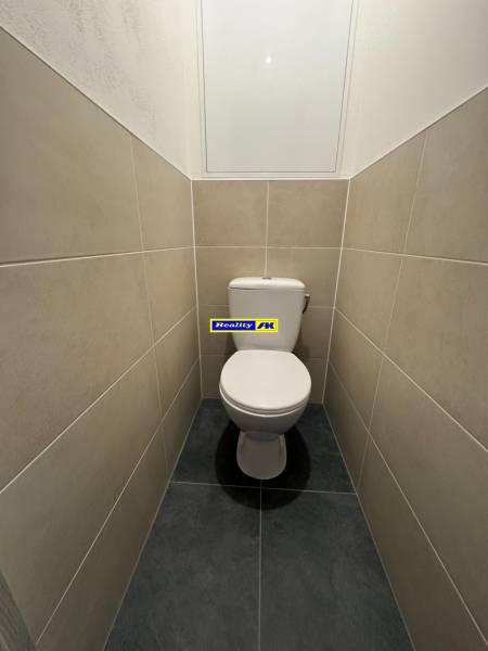 A toilet in a 3-room apartment with light-colored tiles and a simple design.