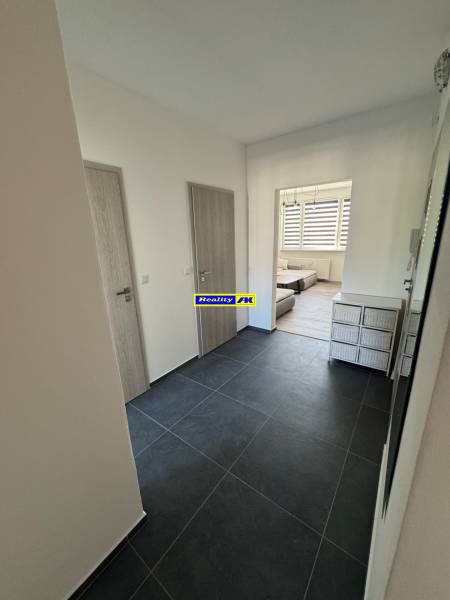 Entrance hallway in a 3-room apartment with dark tiles and light doors.