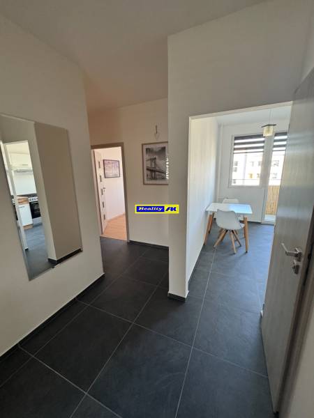 A hallway with dark tiles and a dining room in a 3-room apartment.