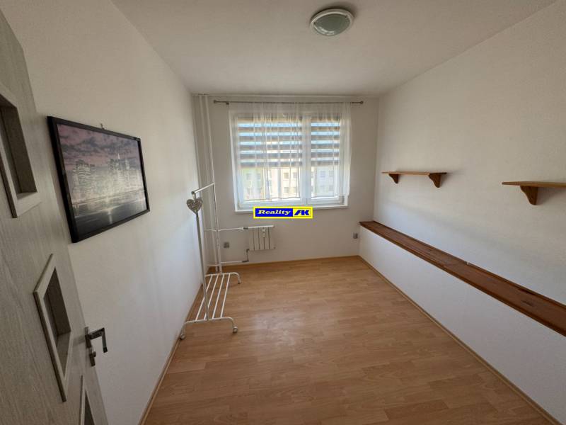 A bright room in a 3-room apartment with a wooden decor floor and wall shelves.