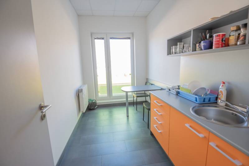 A kitchenette in the office with orange cabinets, a sink, and a seating table.