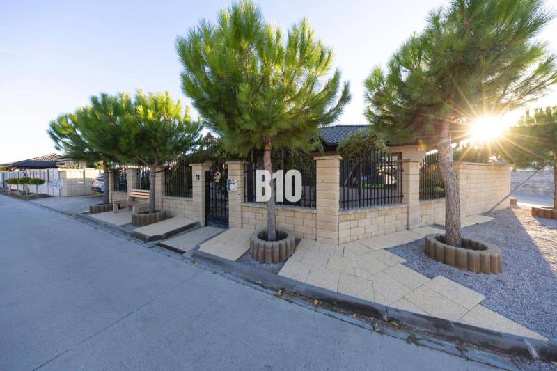 A family house in Most pri Bratislave with a stone fence and tree planting.