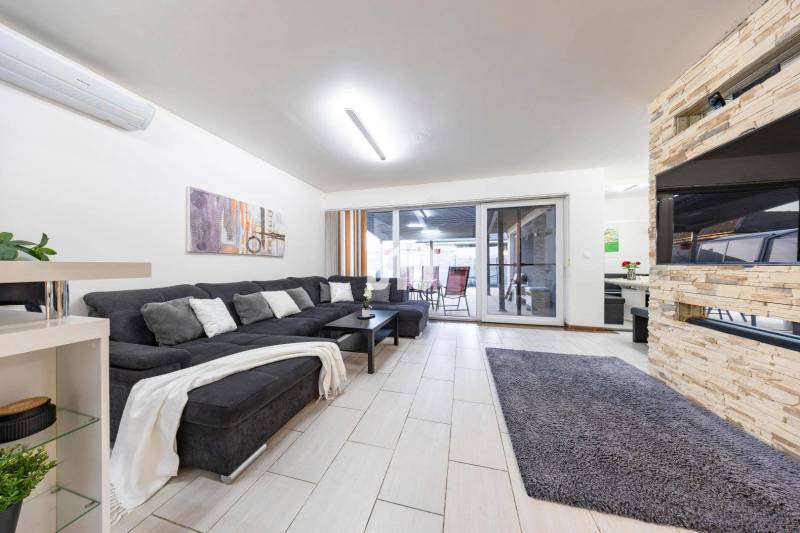 Living room of a family house with a sofa, fireplace, and sliding doors to the terrace.