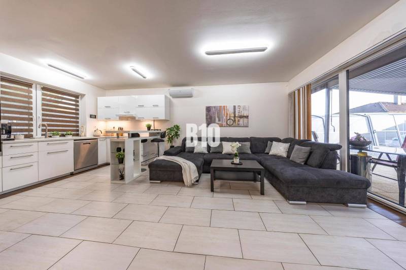 A bright living room in a family house with a kitchen and a large sofa.