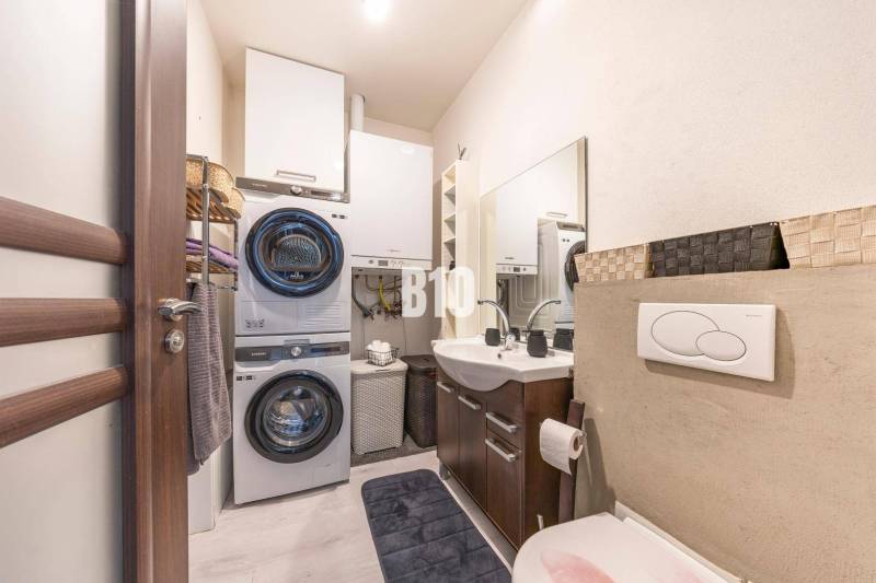 Bathroom in a family house with a washing machine, dryer, sink, and storage space.