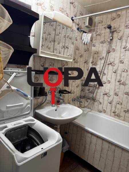 Bathroom in a 3-room apartment with a bathtub, sink, and washing machine, wallpaper decoration.