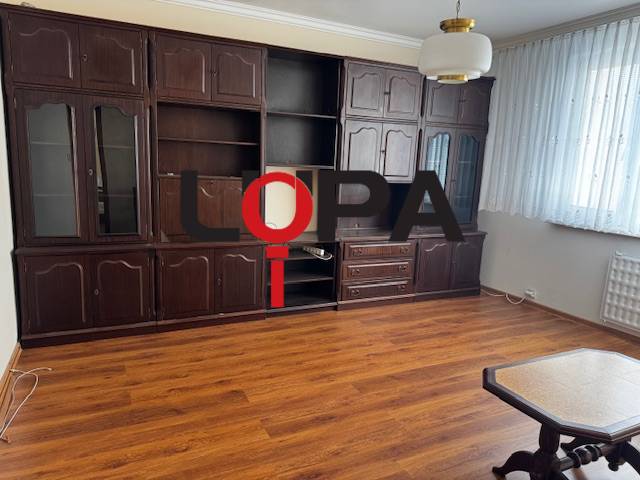Living room in a three-room apartment with a wooden decor floor, dark furniture.