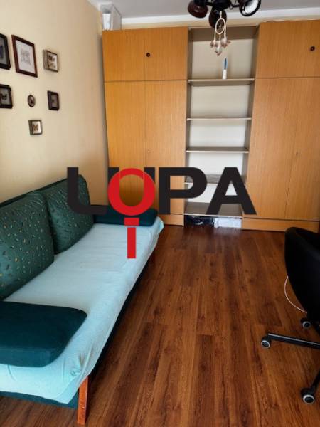 A room in a 3-room apartment with a wood-patterned floor and built-in wardrobes.