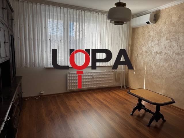 A room with a wooden floor decor and a table in a three-room apartment.