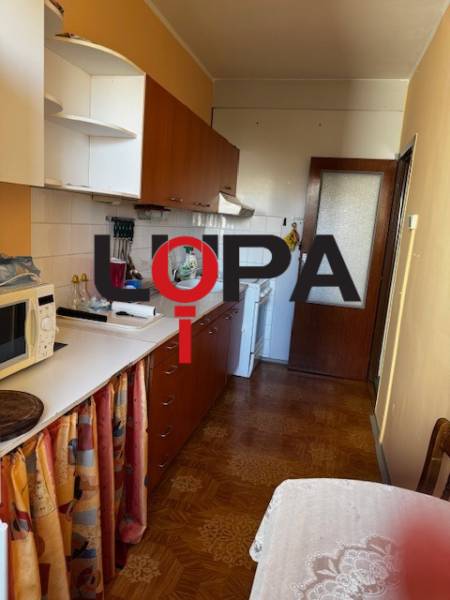 A kitchen in a 3-room apartment with a wooden decor floor, white cabinets, dining table.