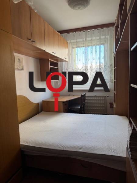 Bedroom in a 3-room apartment with a bed, wardrobes, and a window with lace curtains.